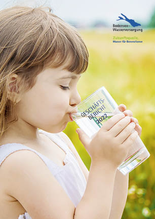 Titelseite des Geschäftsberichts 2022 der Bodensee-Wasserversorgung. Abgebildet ist ein kleines Mädchen mit braunen Haaren, das an einem sonnigen Tag auf einer Wiese aus einem Glas Wasser trinkt. Auf dem Glas ist der Schriftzug ‚Geschäftsbericht 2022‘ zu sehen. Oben rechts befindet sich das Logo der Bodensee-Wasserversorgung mit dem Slogan ‚Zukunftsquelle. Wasser für Generationen‘.